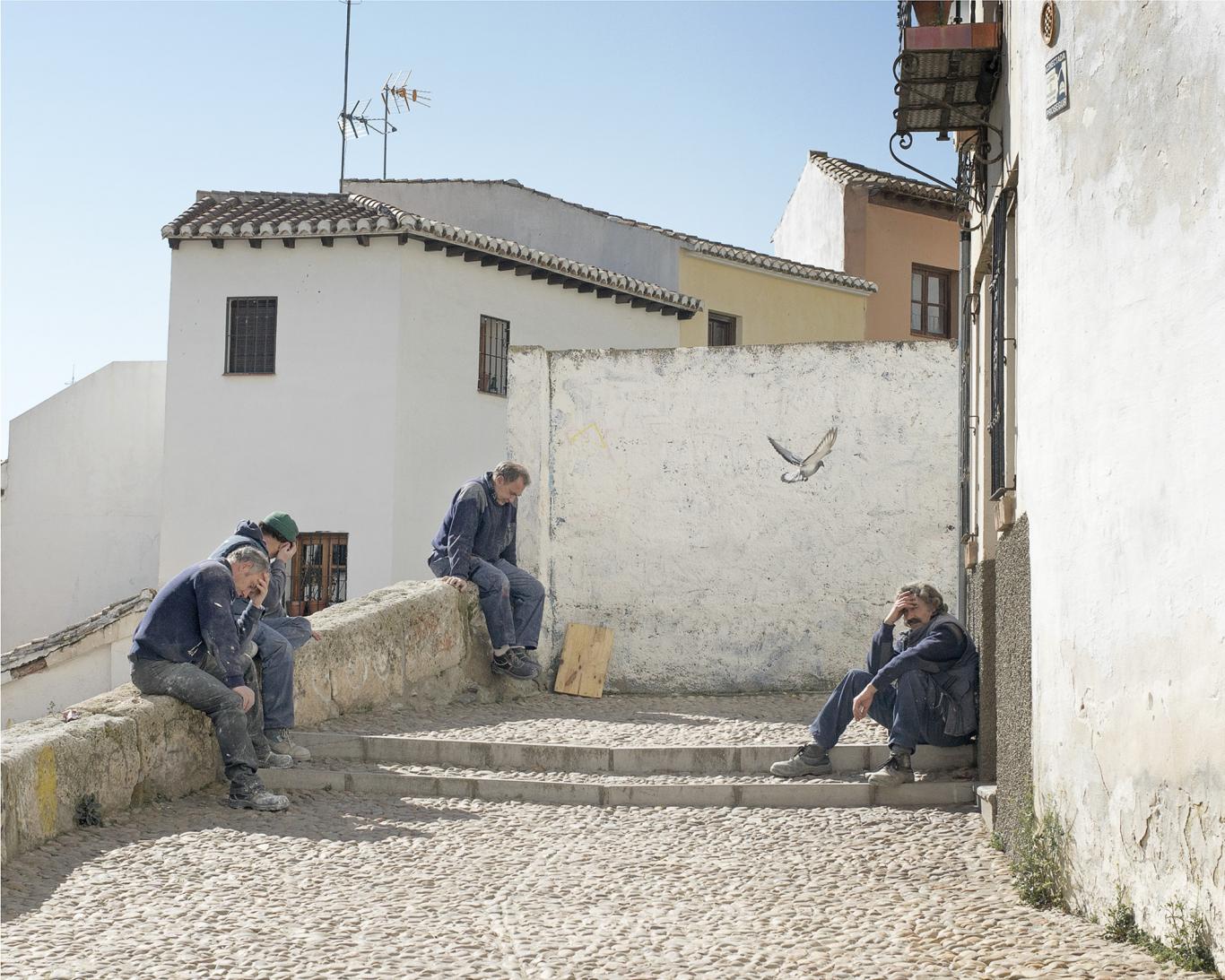Hombres mayeres sentados en unas escaleras de un pueblo