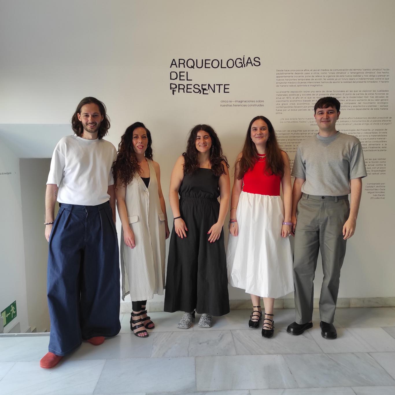 Five young people posing in front of the title of an exhibition that reads Archaeologies of the present