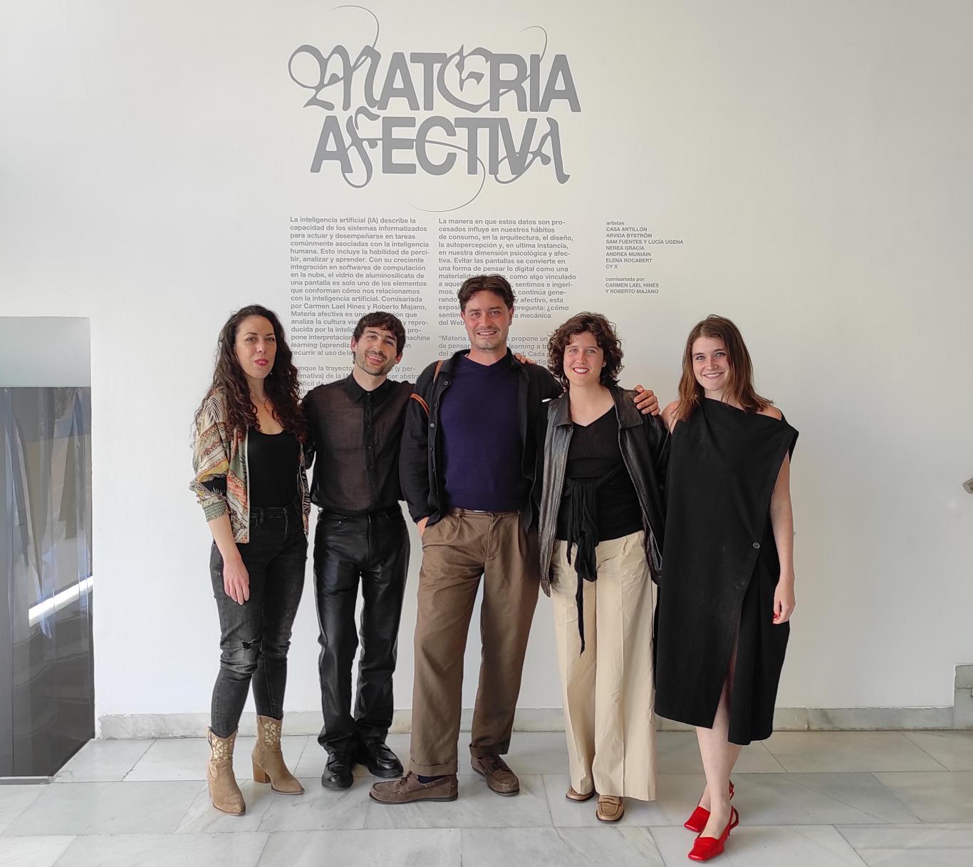 Grupo de jóvenes posando delante del cartel de una exposición donde se lee el título "Materia afectiva"