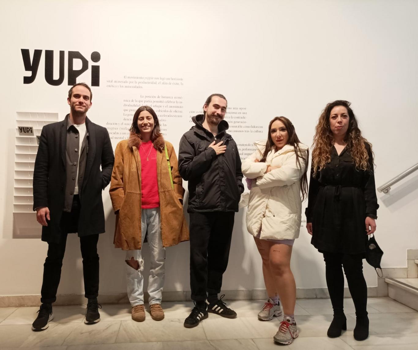 Young people posing in front of the poster of the exhibition that reads yuppie