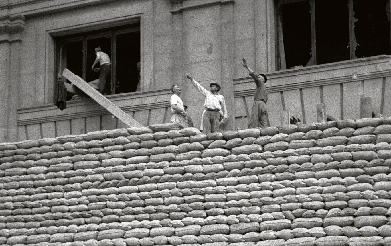 Varios hombres construyen muro de protección con sacos terreros