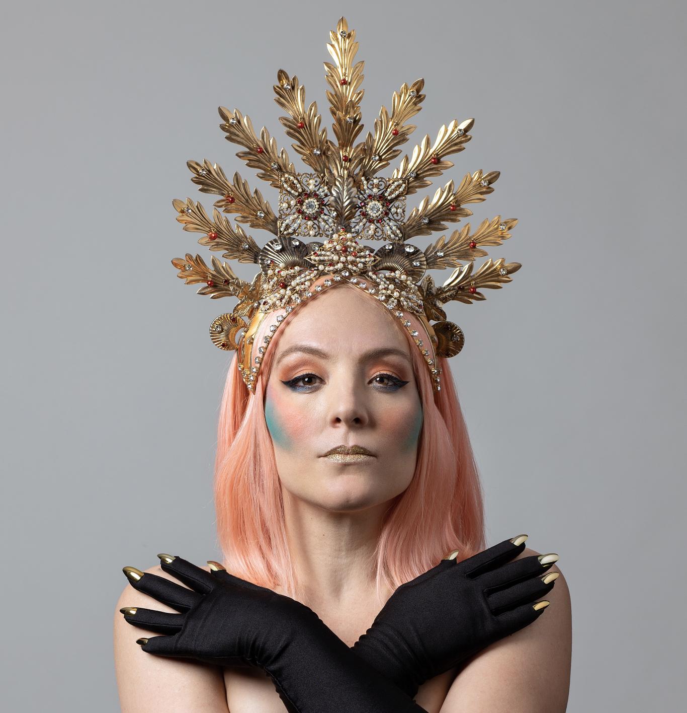 Mujer con pelo rosa, maquillada y coronada