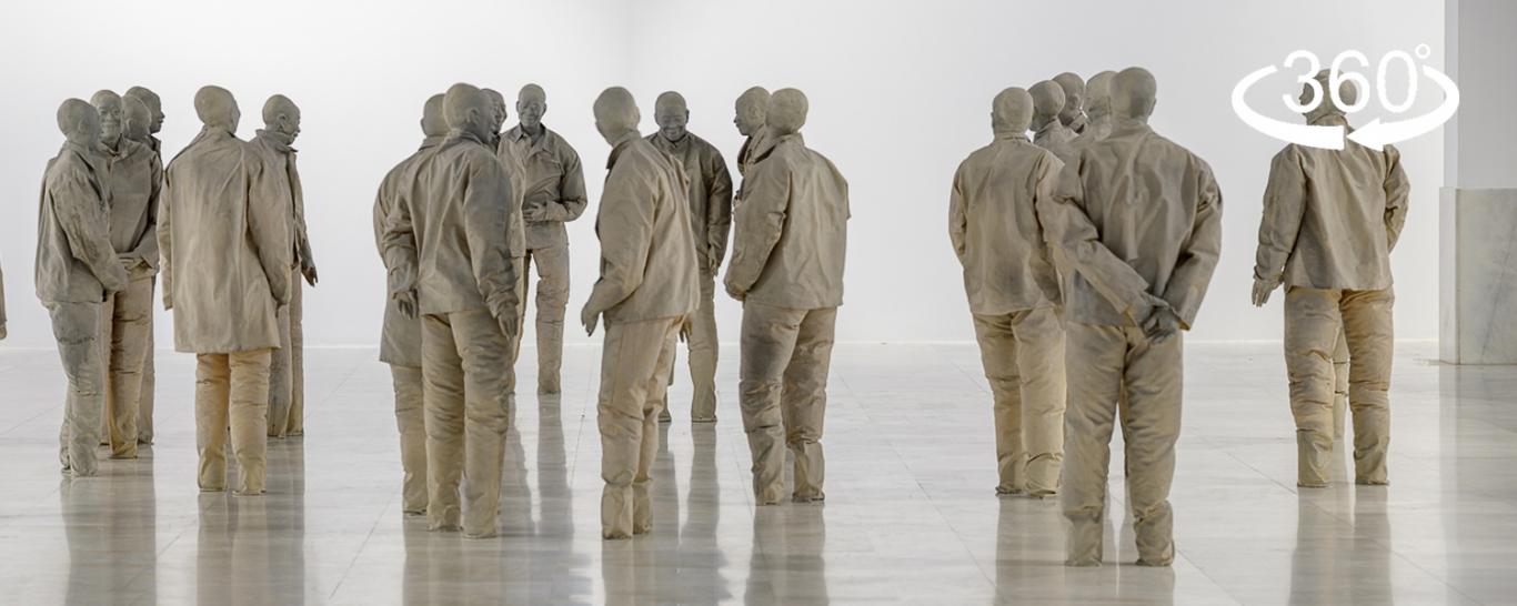 Vista de una sala de exposiciones con esculturas de hombres en color gris