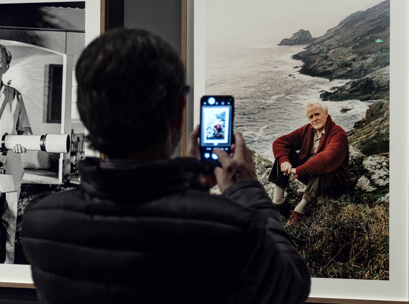 Una persona haciéndole una fotografía a una fotografía en una sala de exposiciones
