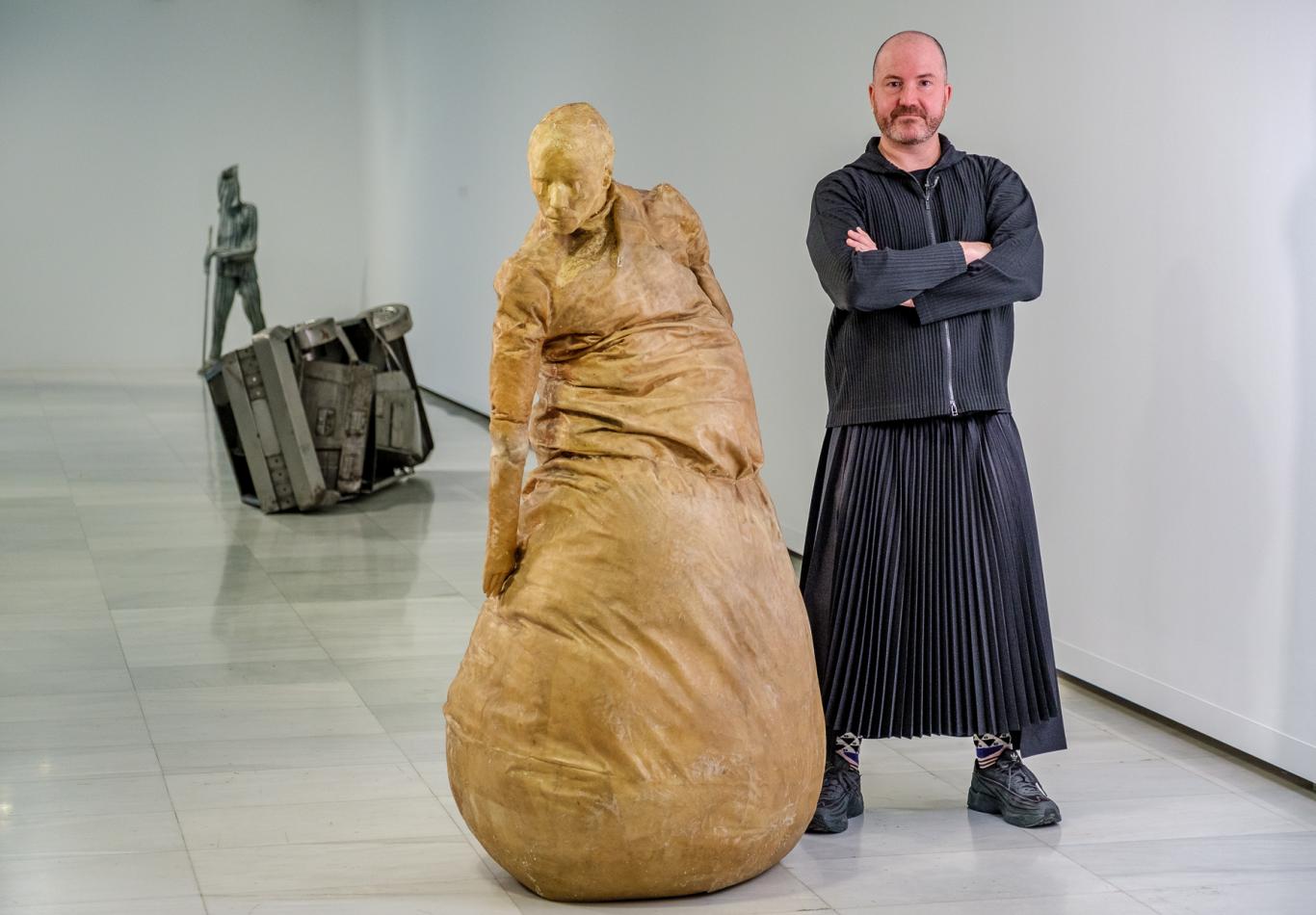 Hombre junto a escultura