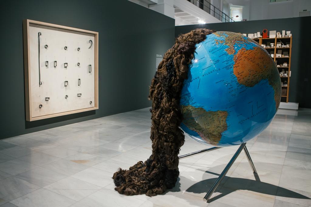 Work by Carmen Calvo that is a large format ball of the world with a large ponytail of hair that falls over it