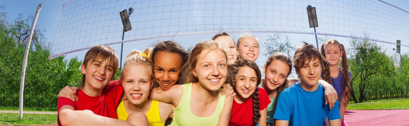 Niños sonrientes sentados en una cancha de voleibol