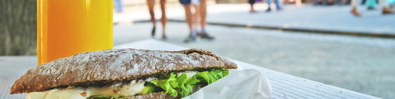 foto de un bocadillo en primer plano y jóvenes corriendo de fondo