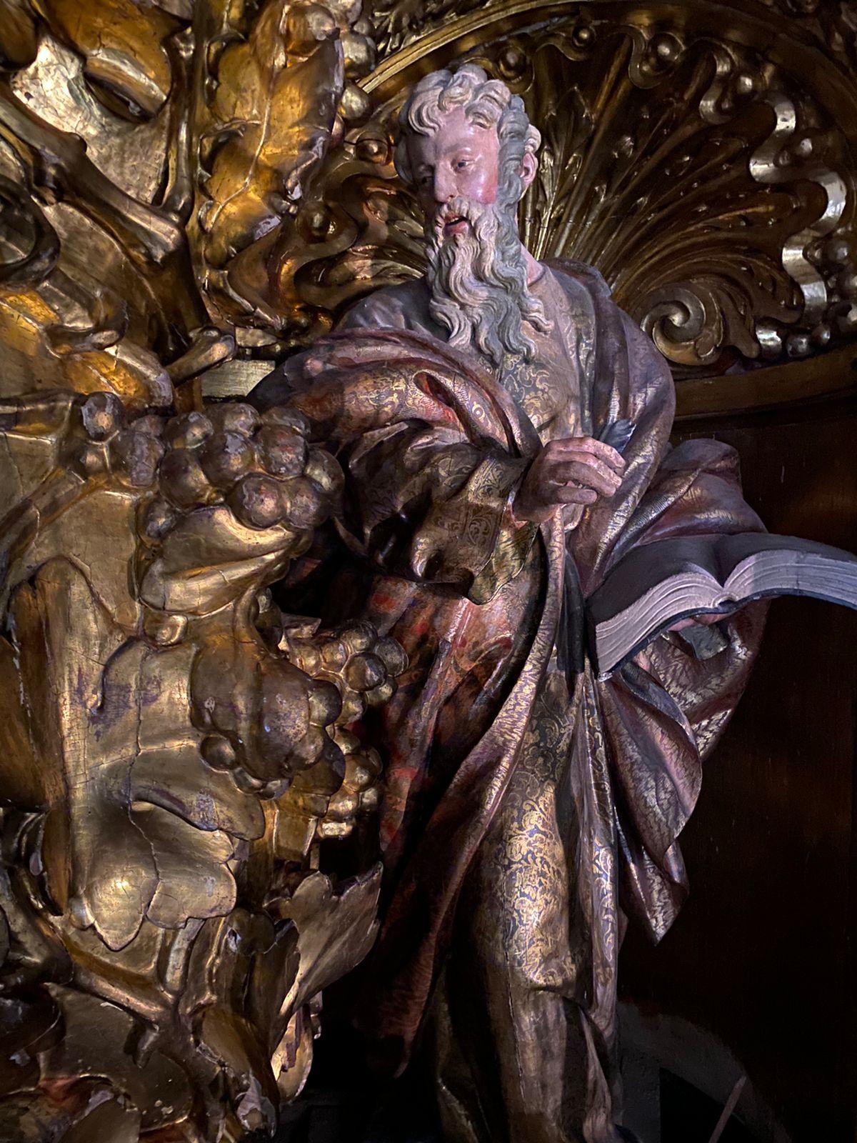 Polychrome and gilded wood carving of a male figure holding a book