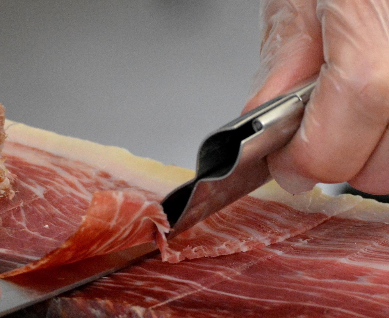 Imagen de una persona cortando una pata de jamón ibérico