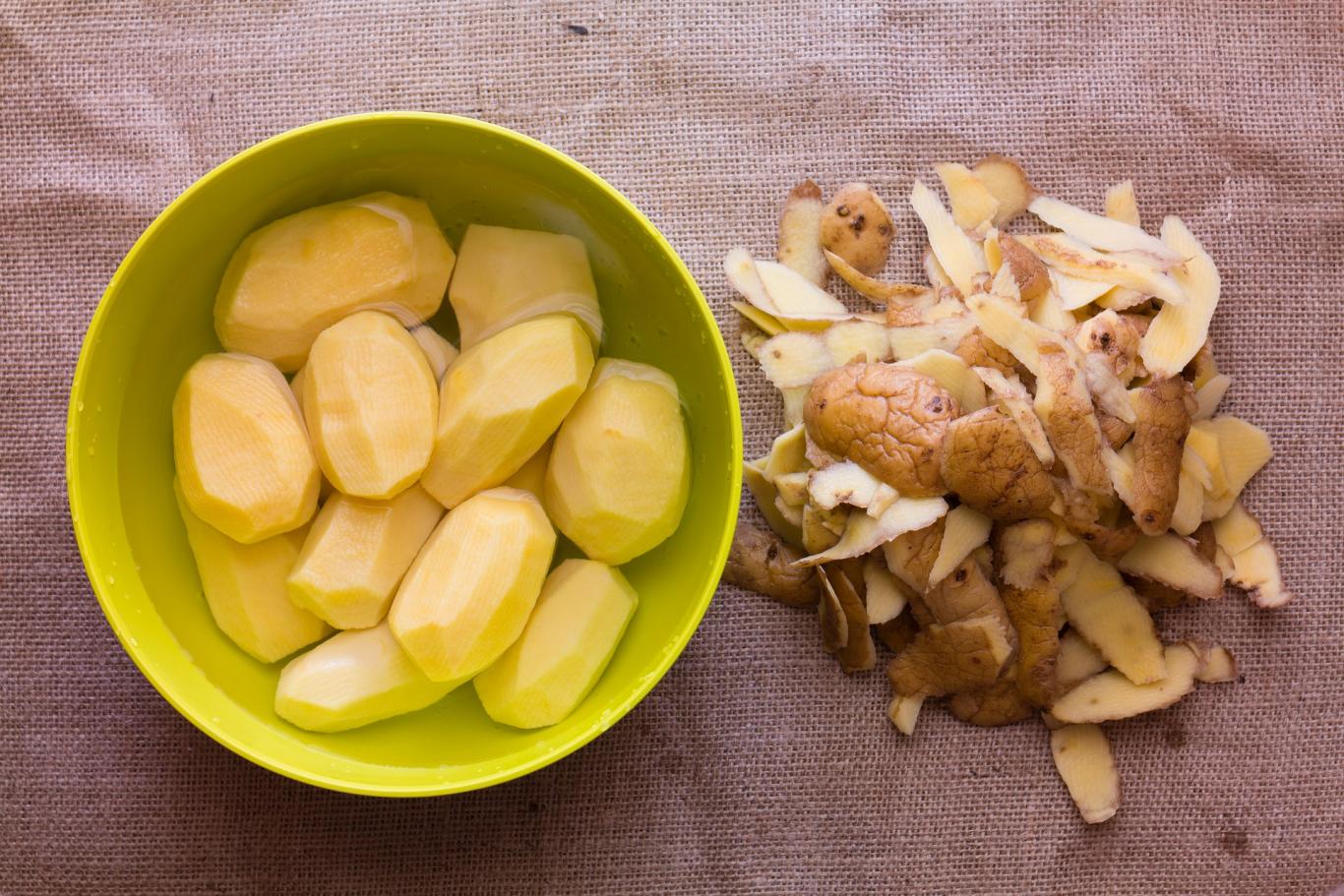 Cuenco con patatas enteras peladas, y piel separada del cuenco