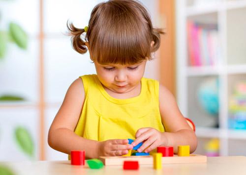 Niña jugando con construcciones de madera