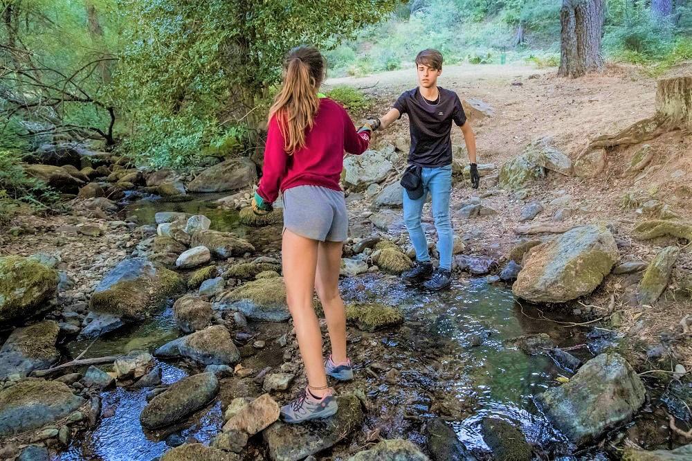 Jóvenes cruzando un río por las piedras