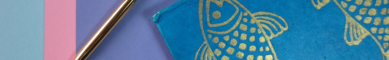 Bolígrafo dorado y cuaderno azul con pez doradp