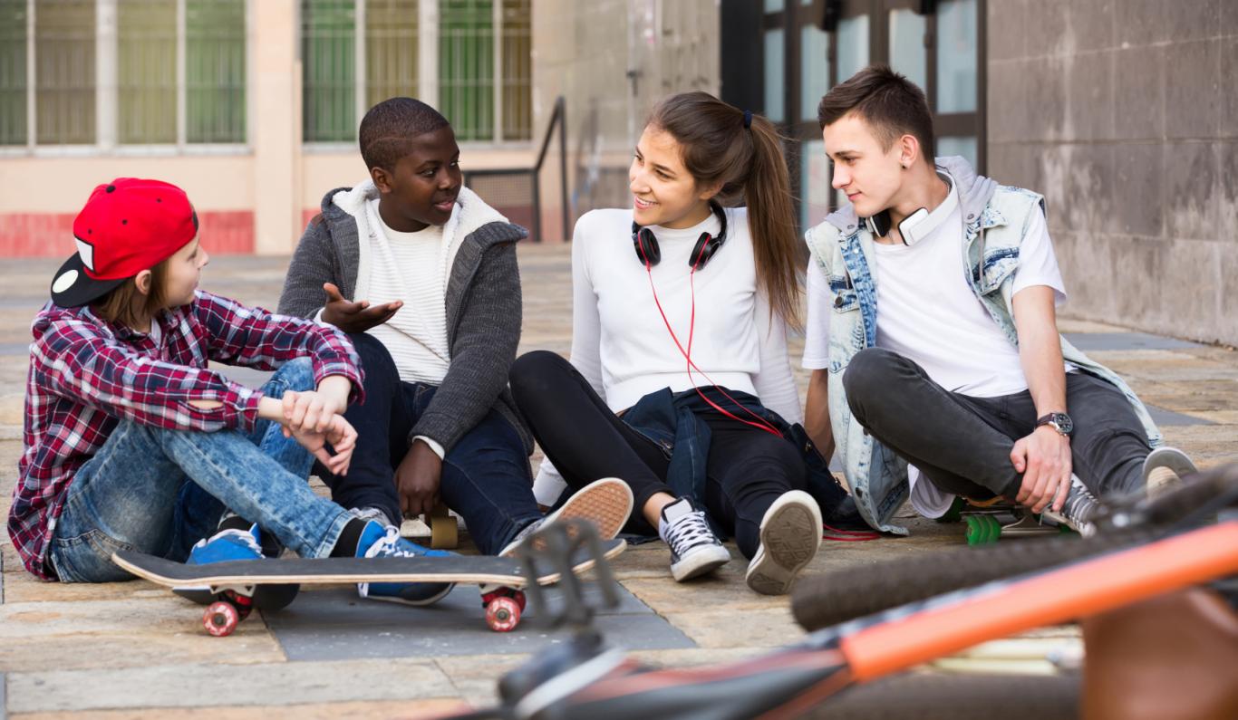 Adolescentes sentados en el suelo charlando