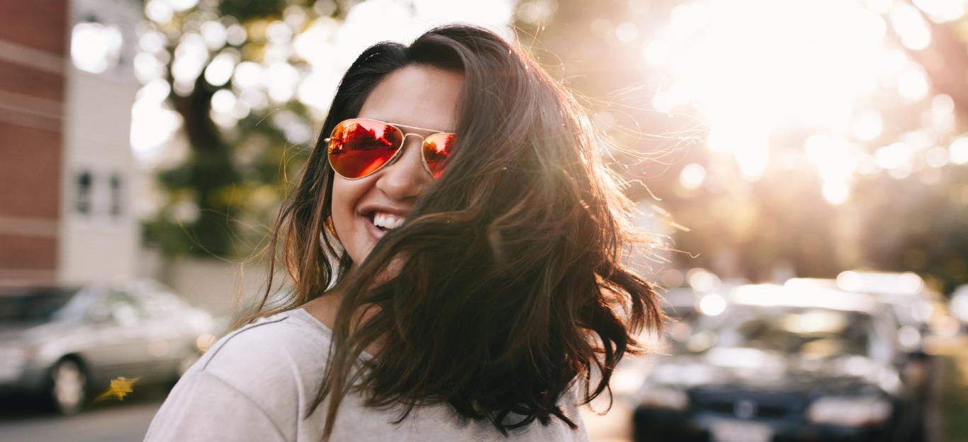 Chica con gafas de sol y pelo suelto sonriendo
