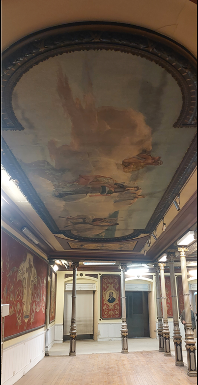 columned hall with wall paintings about music