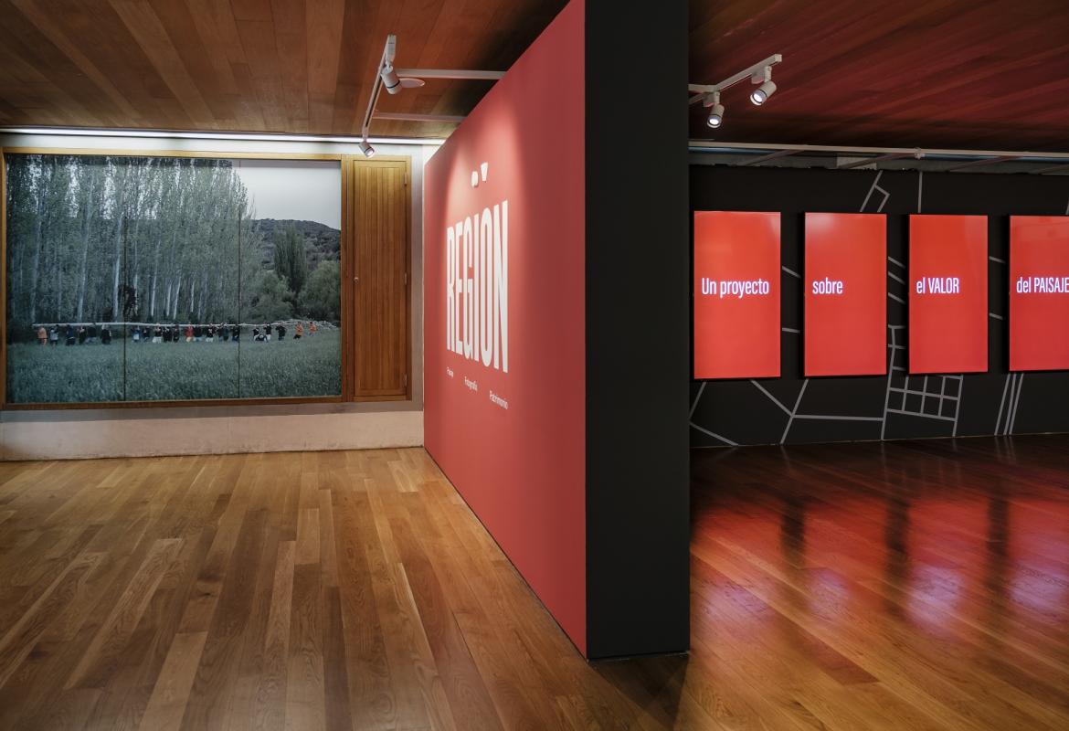 Entrada a la sala de exposiciones, con cartel de la exposición REGIÓN, Paisaje, fotografía y patrimonio y una de las fotografías