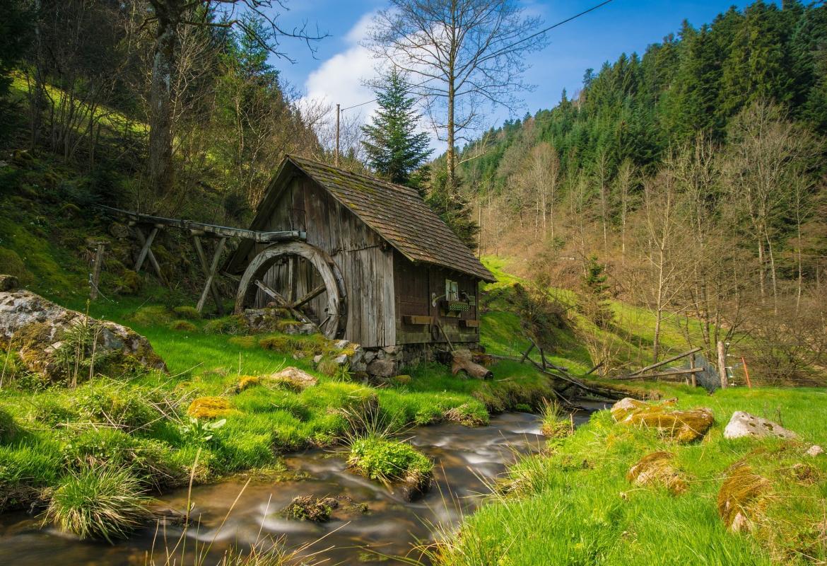 Molino de agua antiguo de madera en el fondo de un valle verde