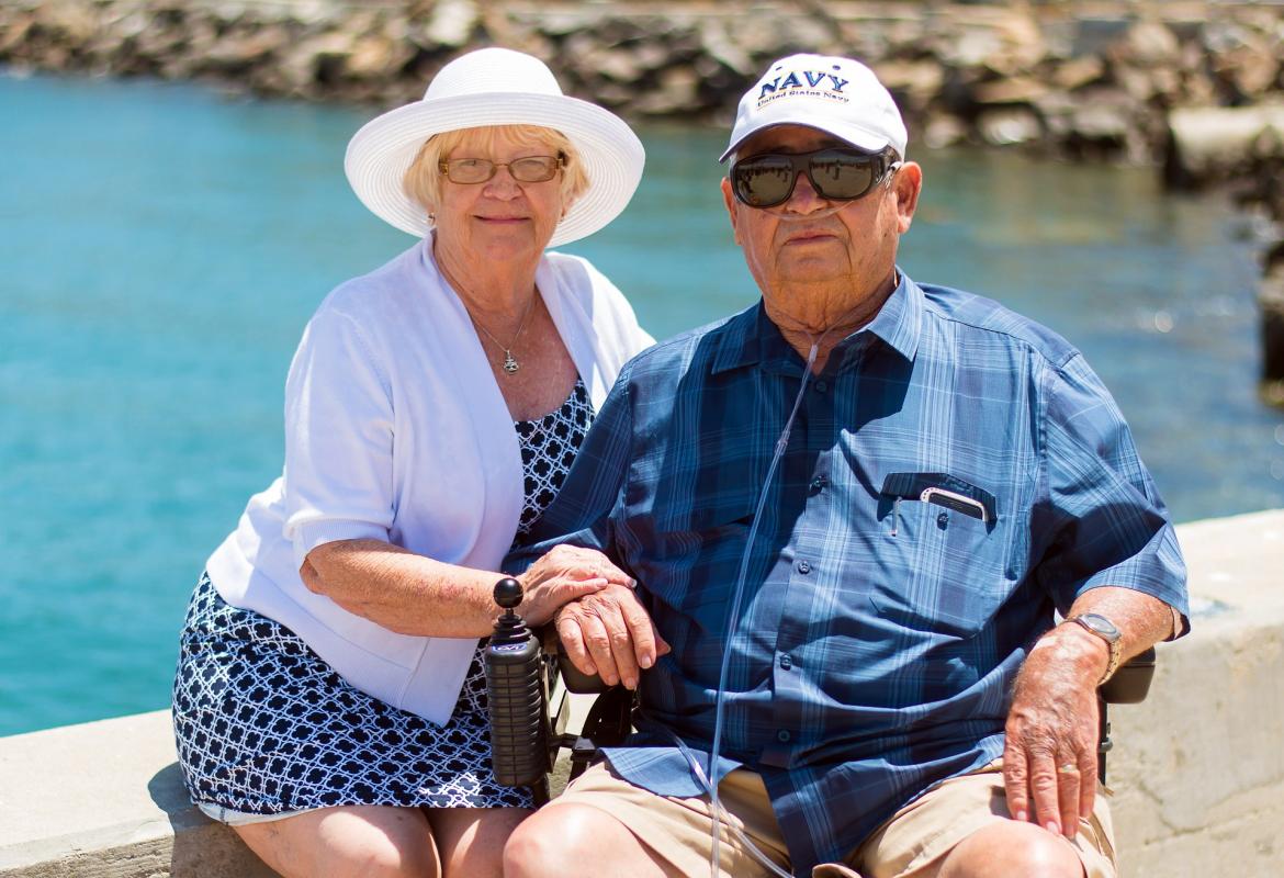 Pareja de mayores en verano. Hombre en silla de ruedas con cánula nasal para oxígeno