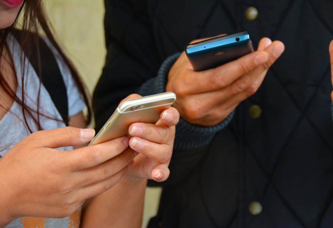 Un hombre y una mujer mirando sus teléfonos móviles