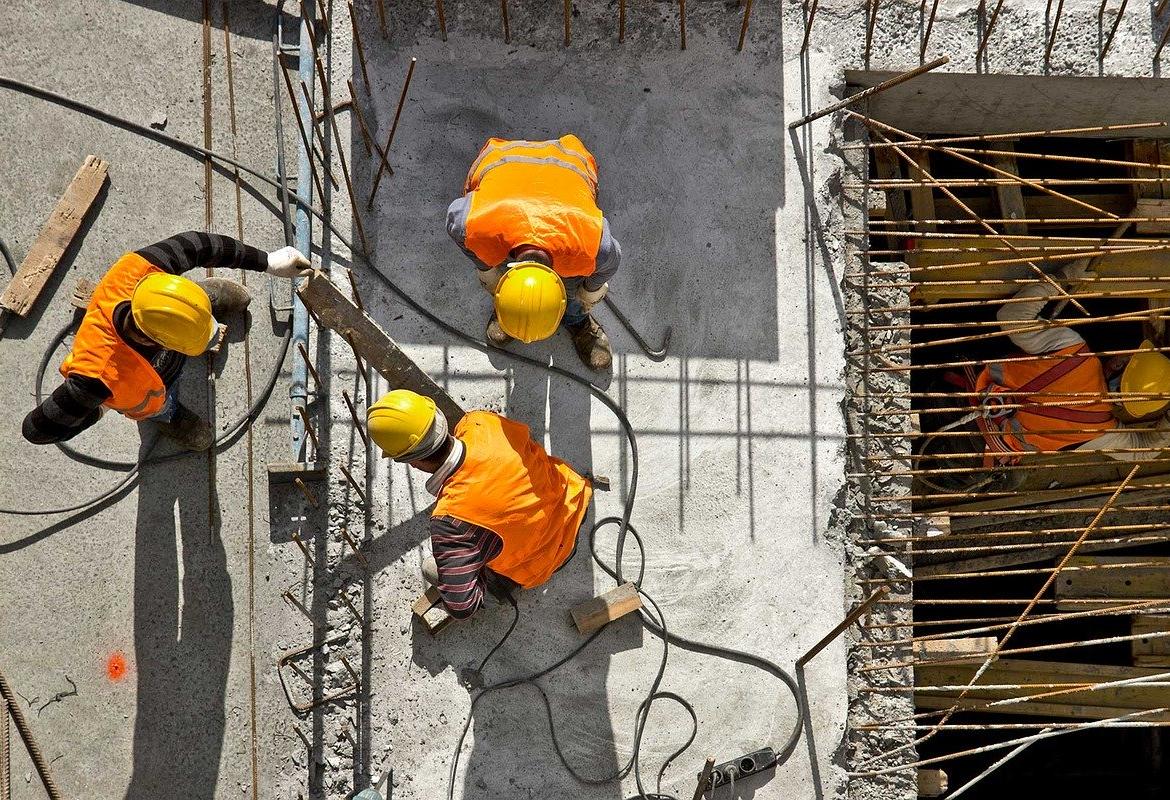 Obreros de la construcción en lo alto de un edificio al sol