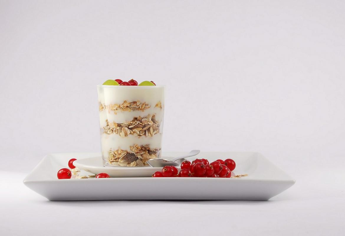 plato con frutos rojos y un vaso con yogur, cereales y frutos