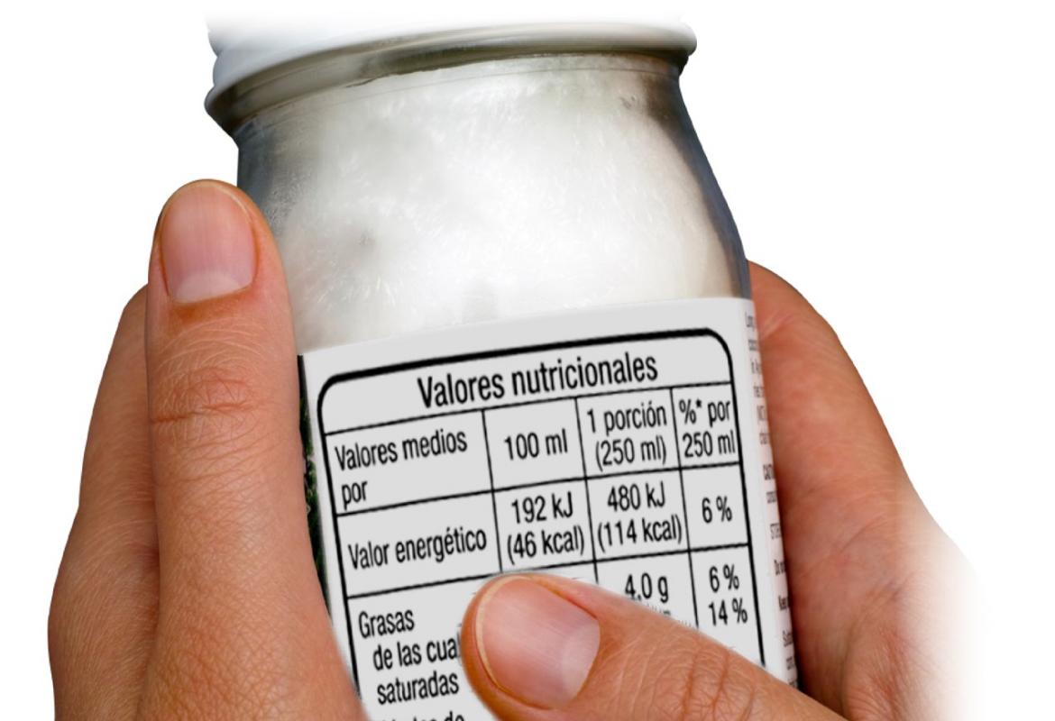 Manos con un yoghurt etiquetado con la información nutricional