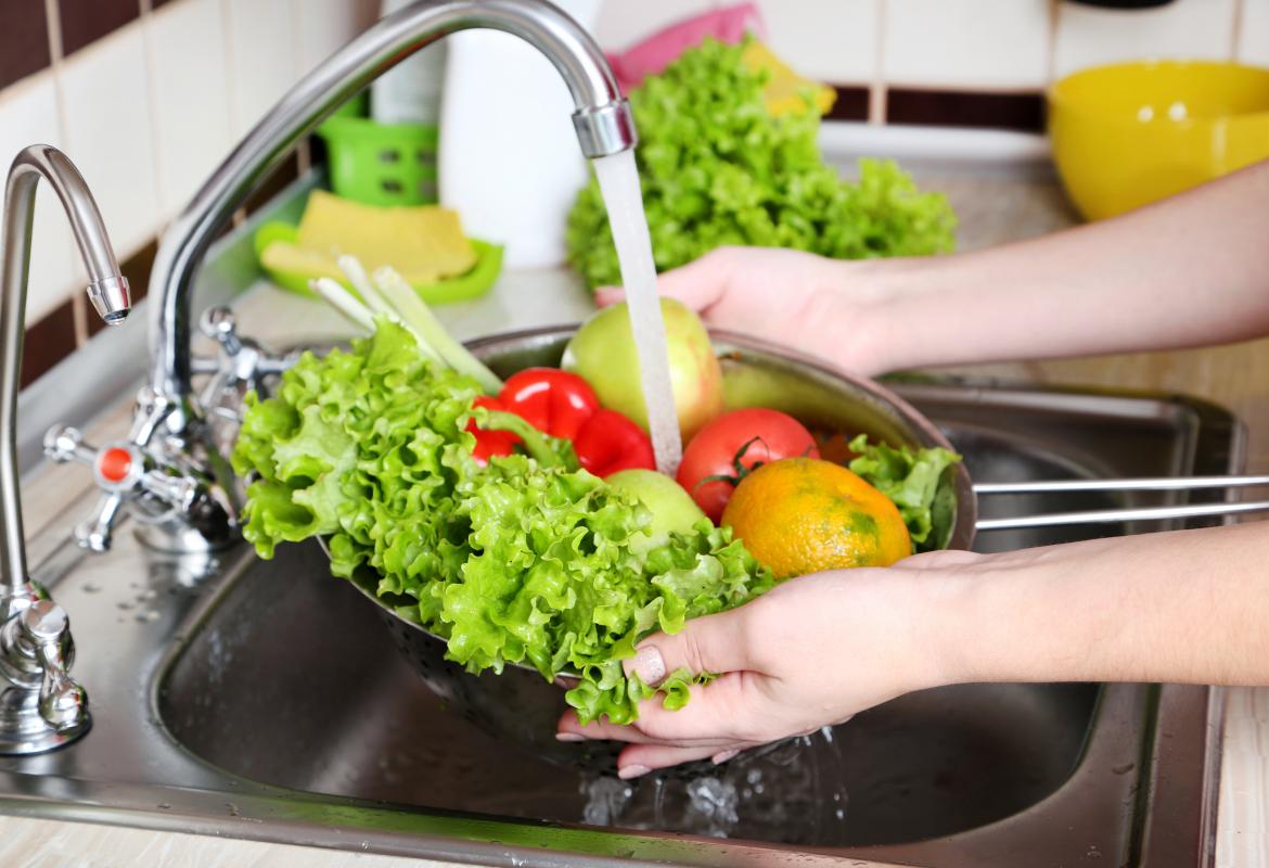 Persona lavando vegetales debajo del grifo