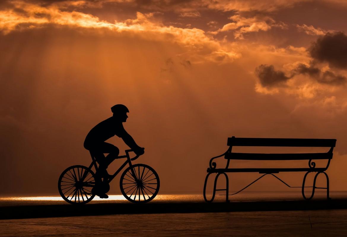 ciclista llegando a un banco al atardecer