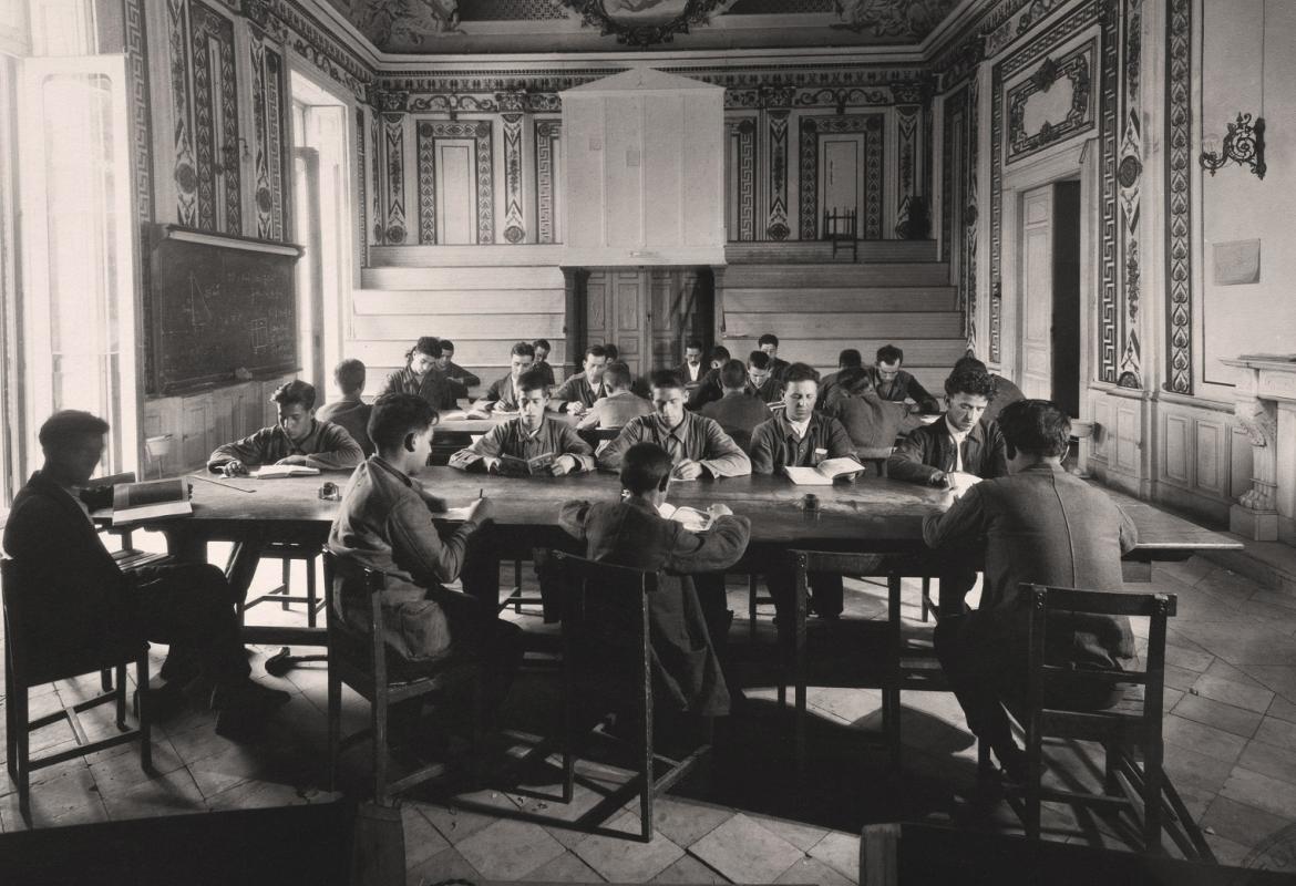 Sala con ventanales a la izquierda y techos decorados donde estudian un grupo de alumnos